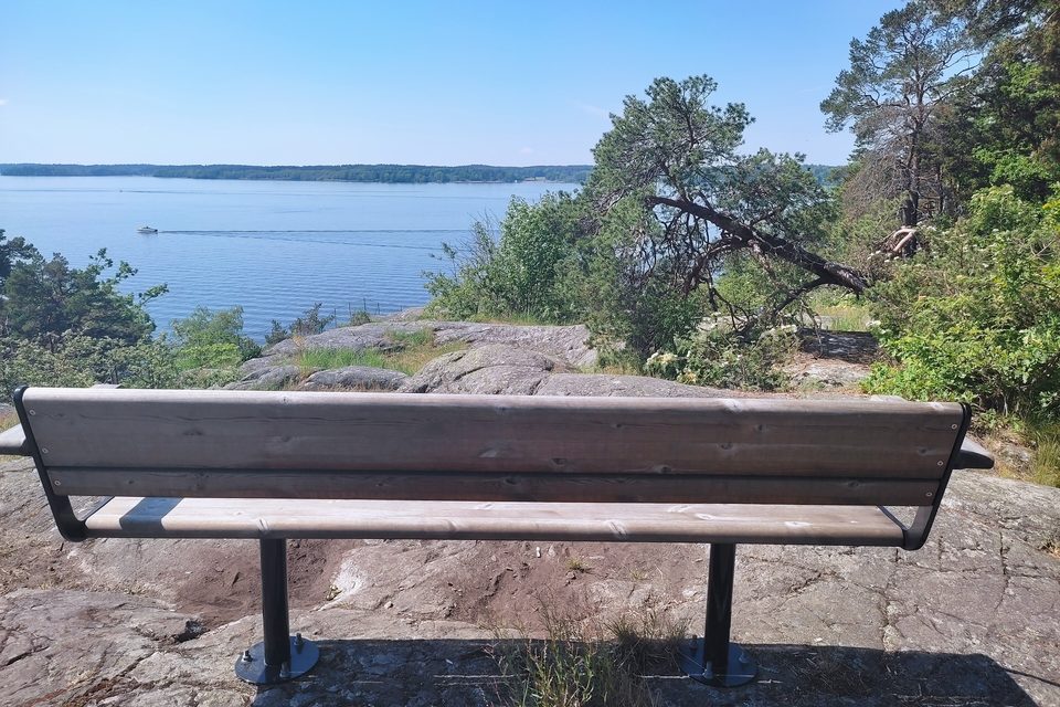 A wooden bench on a rocky viewpoint overlooking calm water