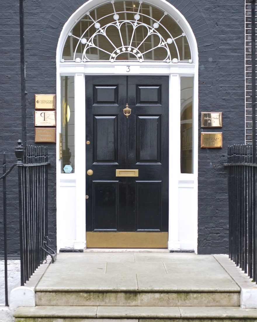 A black panelled front door with a fanlight in a white Georgian doorcase
