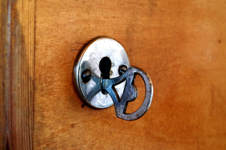 A key turned in a round metal lock plate on a wooden door