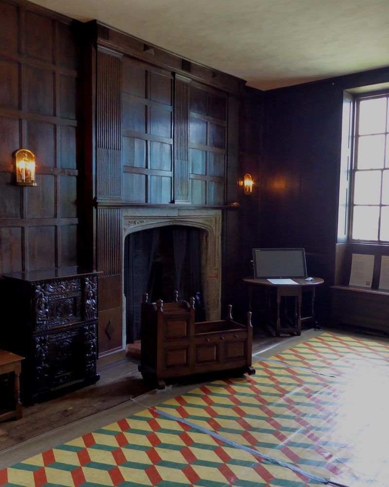 A dark oak-panelled room with a fireplace, a small table and chairs