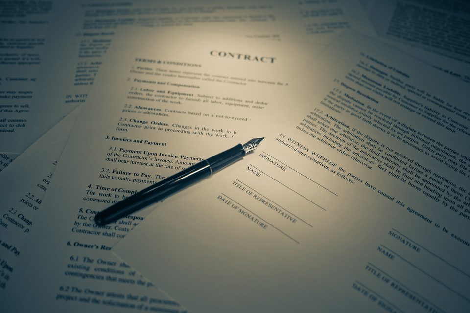 A pen resting on a printed contract under a soft spotlight