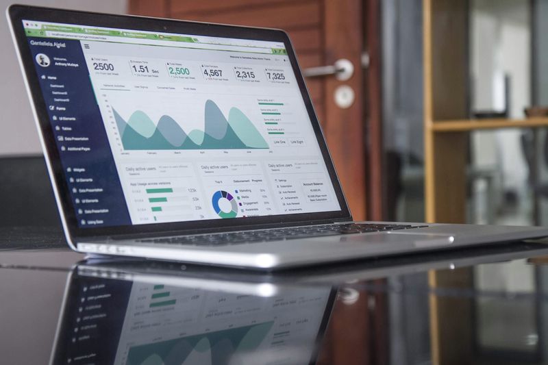 A laptop on a glass desk showing an analytics dashboard with charts