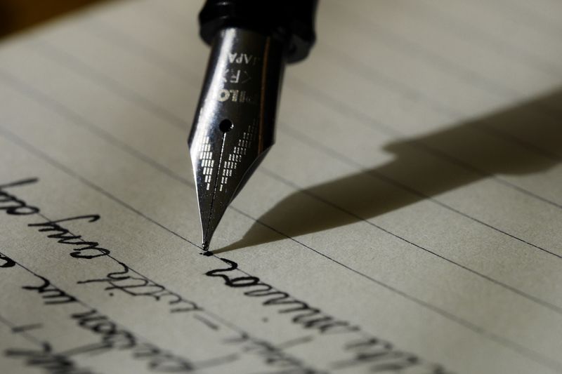 A fountain pen writing notes in ink on lined paper