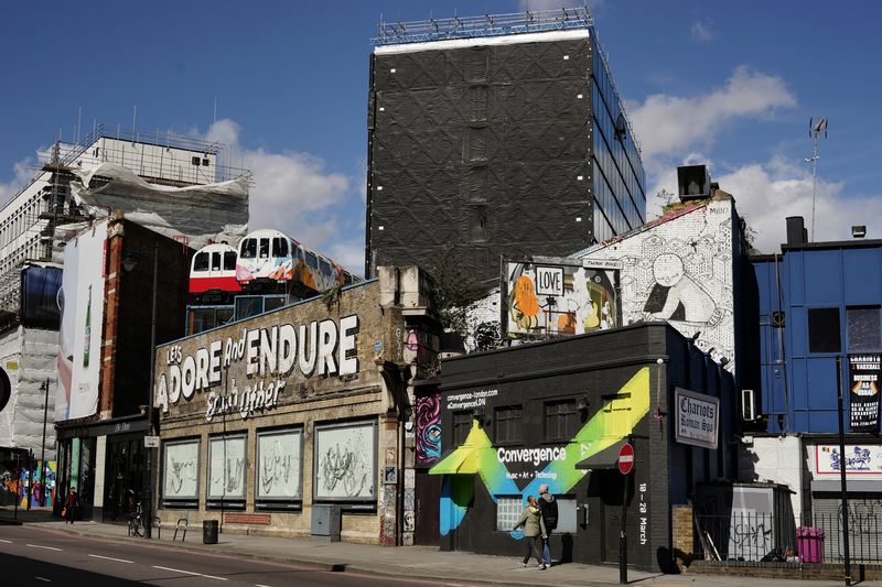 Street art and older shopfronts with a modern tower behind, in Shoreditch, London
