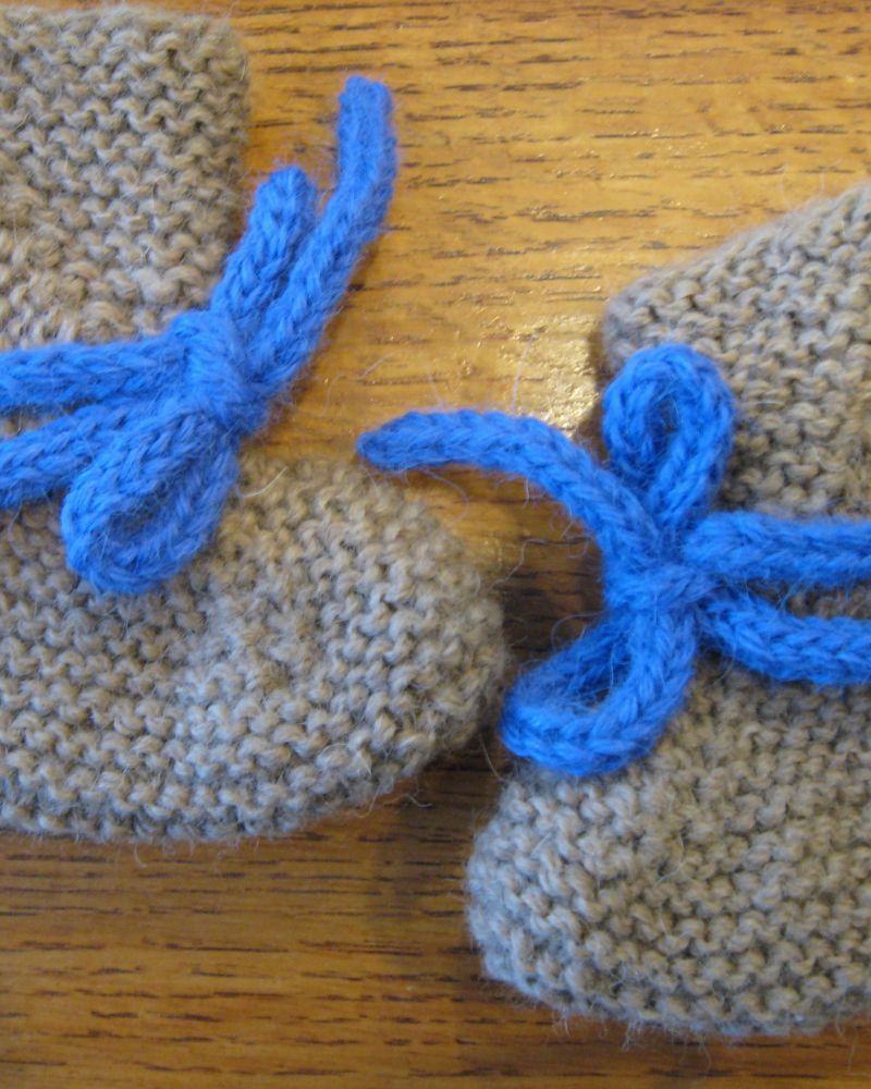 A pair of grey hand-knitted baby bootees with blue ties
