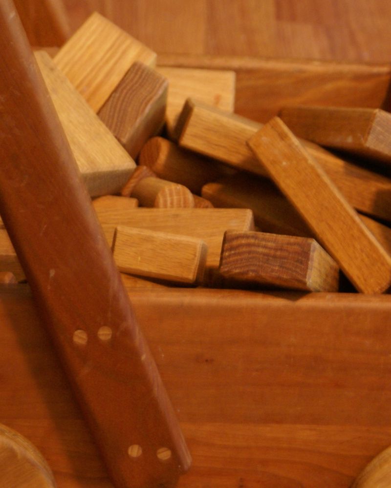 Wooden building blocks piled in a wooden toy wagon