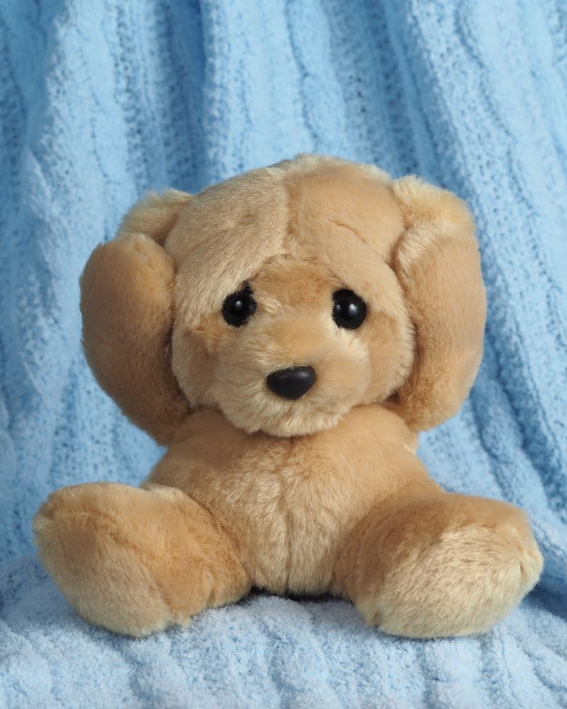 A plush teddy bear sitting on a soft blue knitted blanket