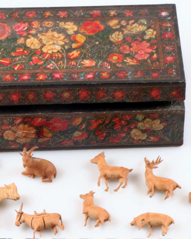 Small carved wooden animal figures in front of a painted wooden box