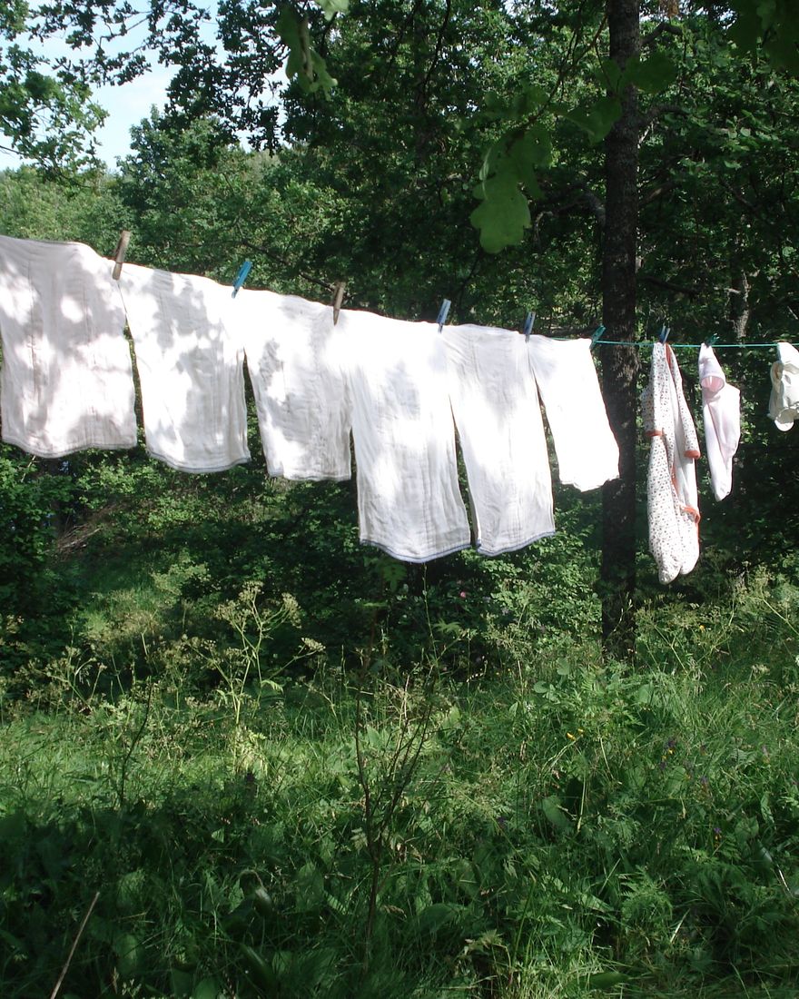 White cloth nappies drying on a washing line in a sunny garden