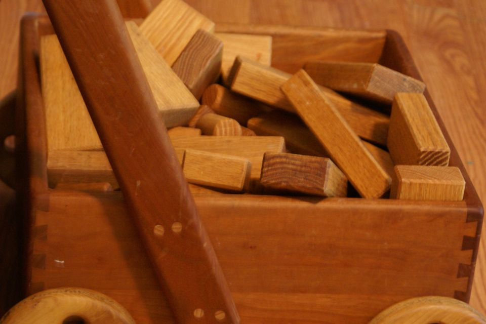 Wooden building blocks piled in a wooden toy wagon