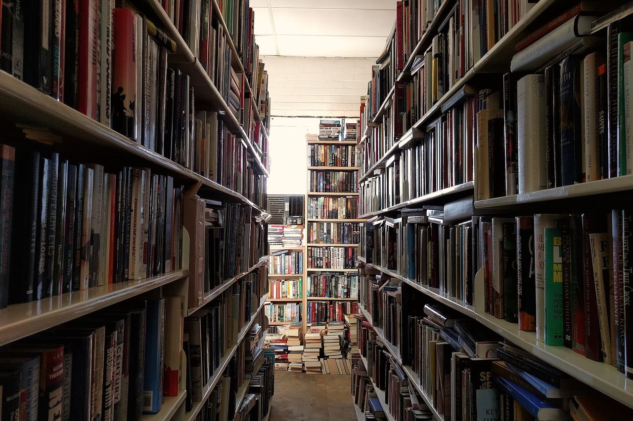 A narrow aisle between tall shelves of secondhand books