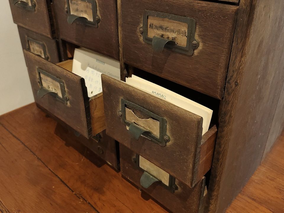 A small wooden cabinet of index-card drawers, two left open