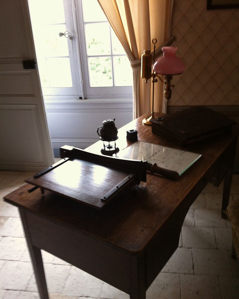 A small writing desk set beside a tall window