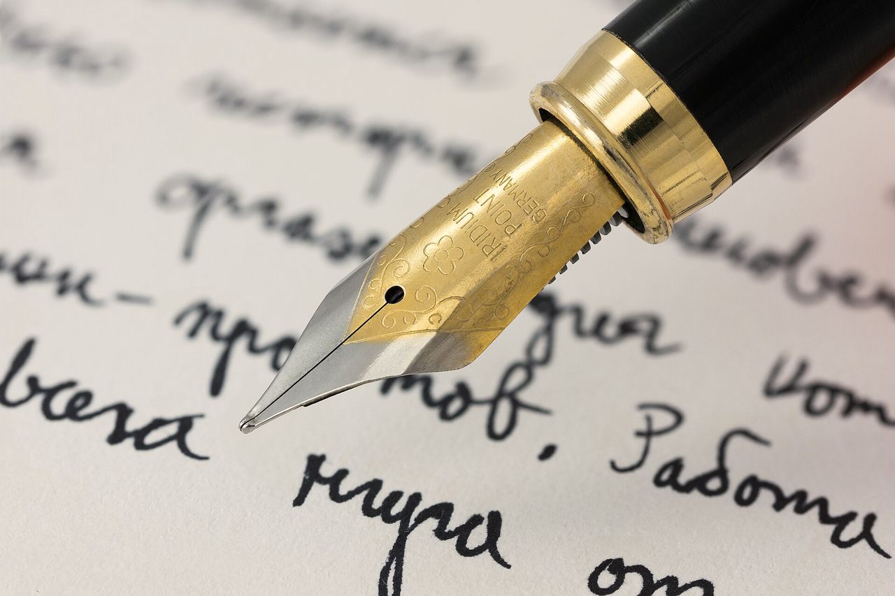A fountain pen nib writing a line of handwriting