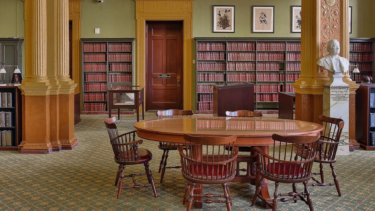 A quiet library reading room with a round table and bookcases