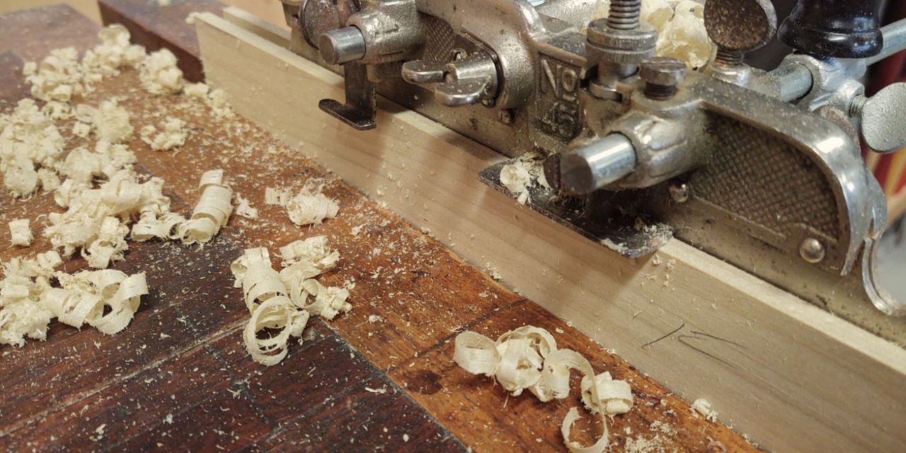 Curled wood shavings beside a metal hand plane on a bench