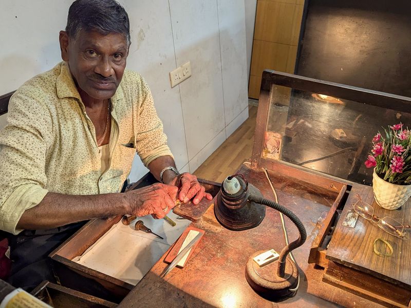 A goldsmith working at a low bench in his workshop