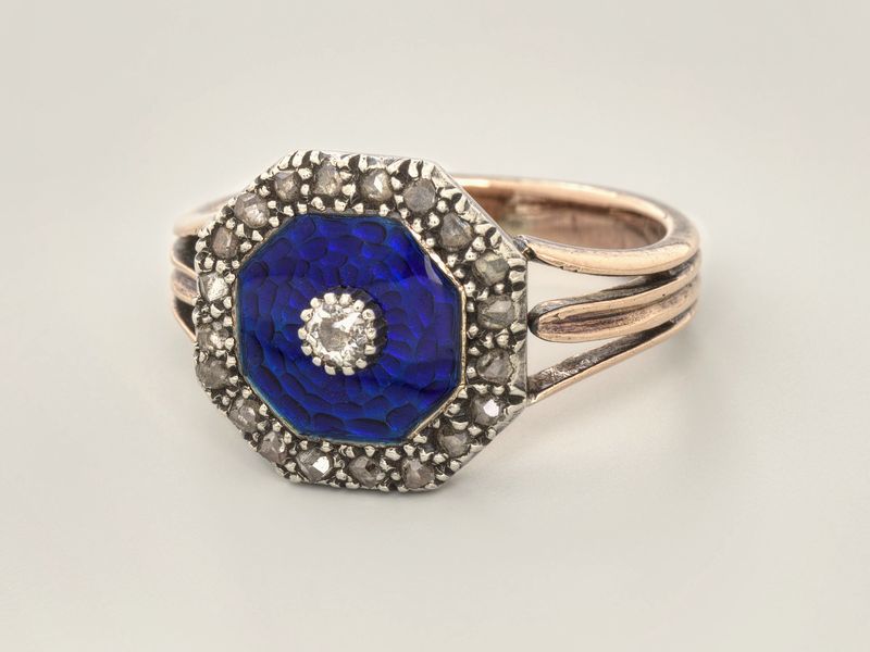 A ring with an octagonal blue enamel face edged and centred with small diamonds, on pale grey, library photograph shown for style