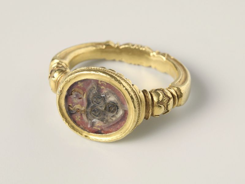 A gold signet ring with a painted coat of arms set under rock crystal, on pale grey, library photograph shown for style