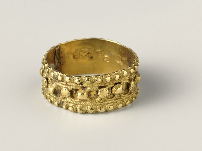 A gold band decorated with a ring of filigree circles between two beaded edges, on pale grey, library photograph shown for style