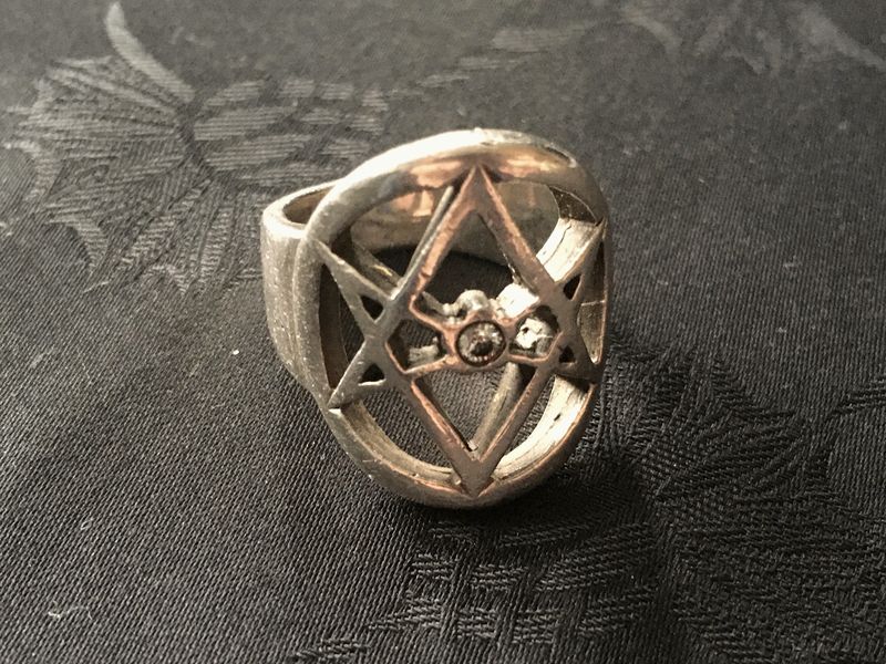 A silver ring with a pierced star pattern on a dark surface