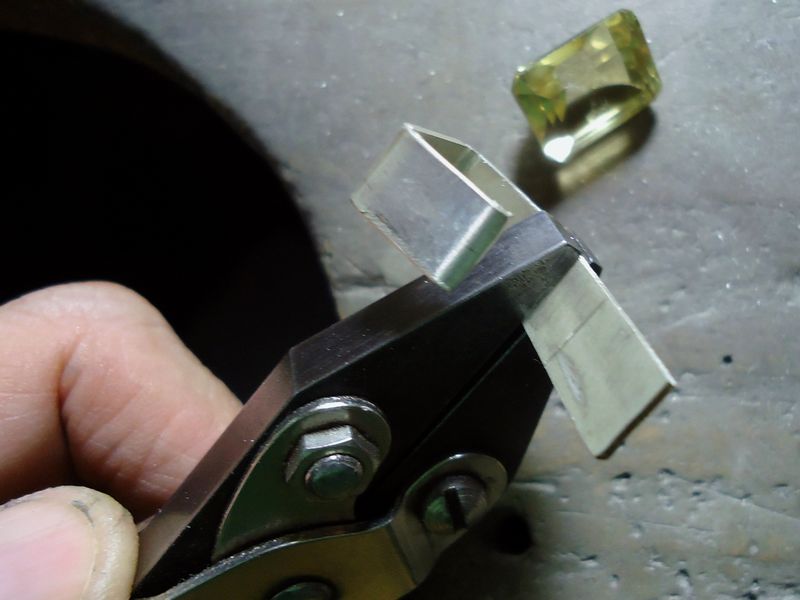 Hands bending a small piece of wire with a pair of pliers