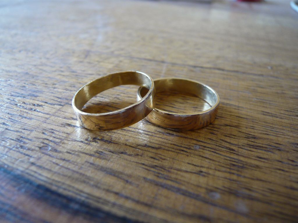 Two plain gold wedding bands lying together on a worn wooden table