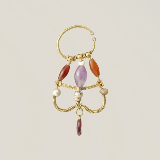 A gold hoop earring hung with carnelian, pearl and amethyst beads, on pale grey, library photograph shown for style