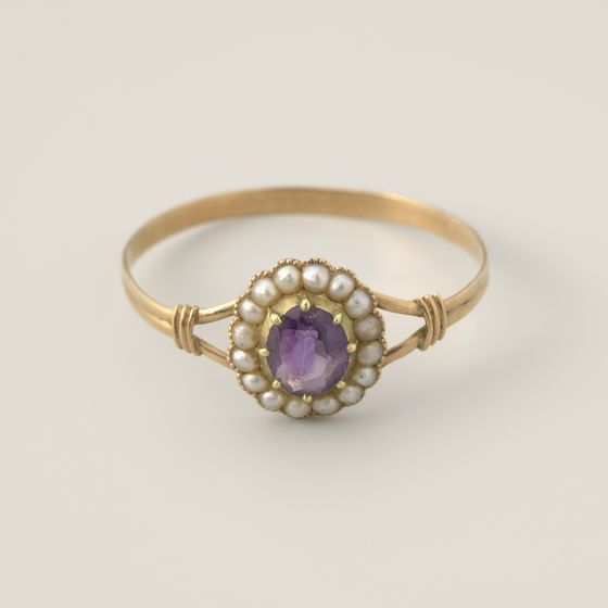 A gold ring with an amethyst surrounded by small pearls, on pale grey, library photograph shown for style