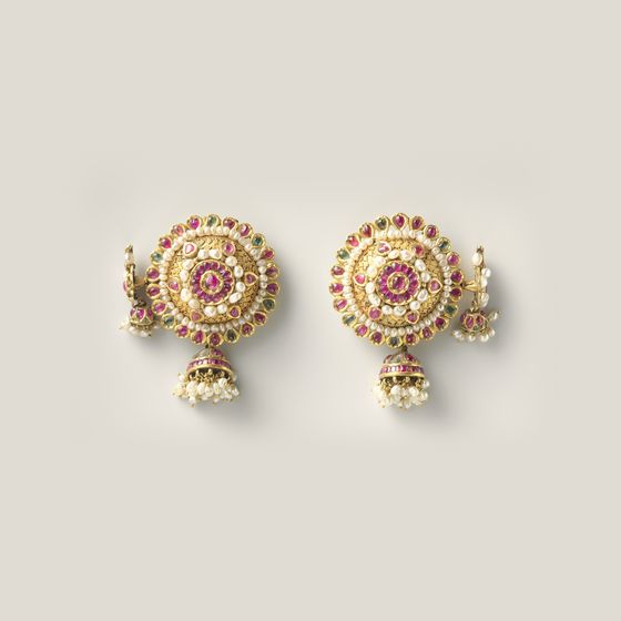 A pair of rosette earrings set with red and green stones and edged with pearls, on pale grey, library photograph shown for style
