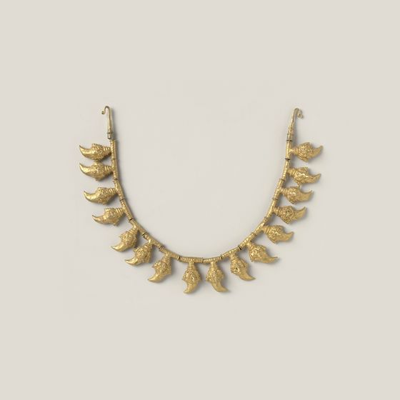 A gold necklace of small claw-shaped links, on pale grey, library photograph shown for style