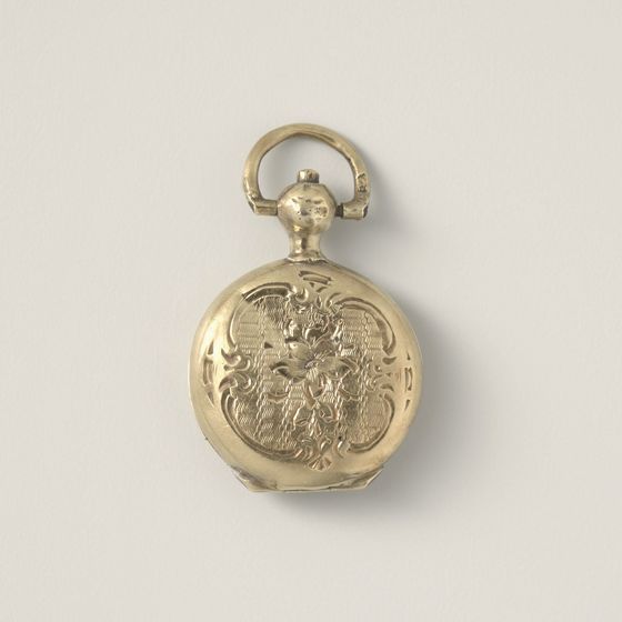 A small round gold locket engraved with scrollwork, on pale grey, library photograph shown for style