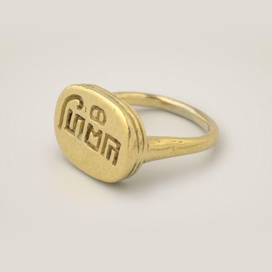 A solid gold signet ring with an inscription in Old Javanese script engraved on its face, on pale grey, library photograph shown for style