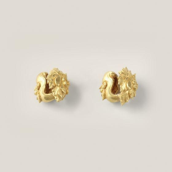 A pair of small ornate gold earrings, on pale grey, library photograph shown for style
