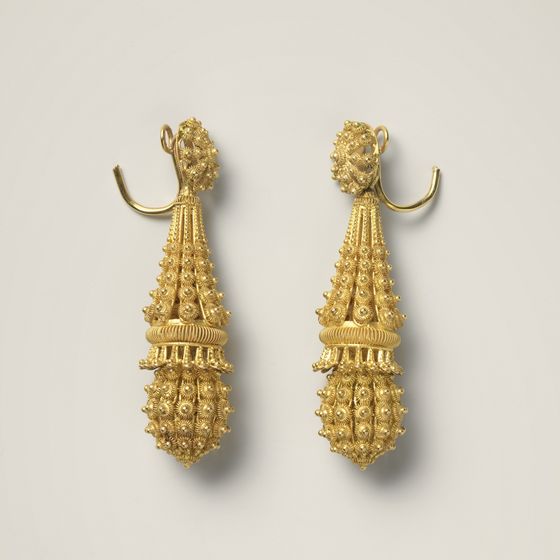 A pair of long gold filigree drop earrings, on pale grey, library photograph shown for style