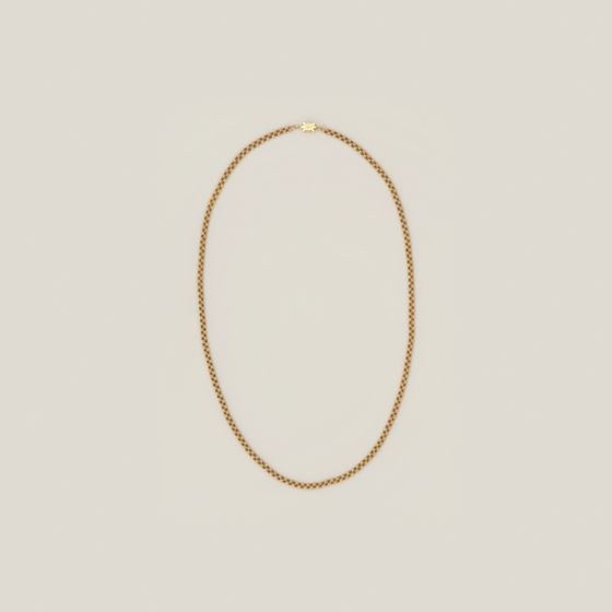 A long fine gold chain laid in a loop, on pale grey, library photograph shown for style