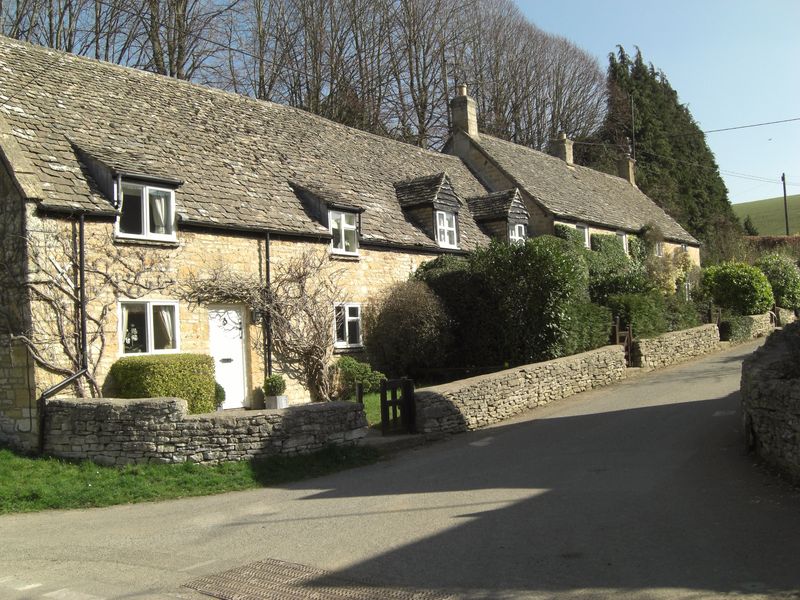 A row of Cotswold stone cottages along a village lane