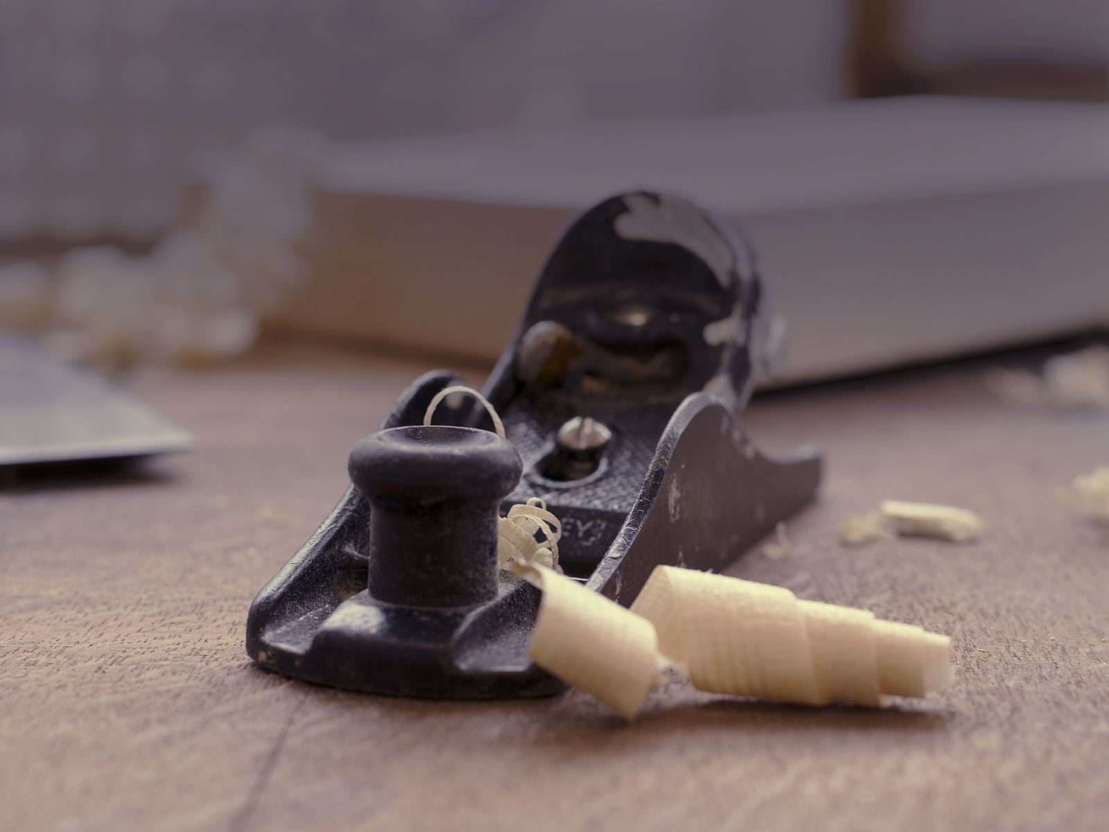 A hand plane resting on a board among curled wood shavings