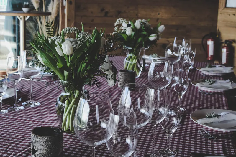 A long table laid for dinner with glasses and white flowers