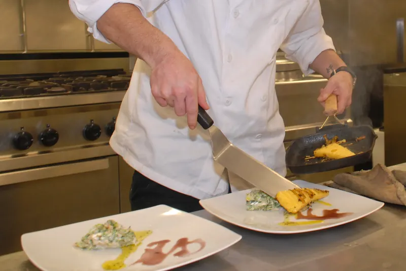 A cook plating a dish in the kitchen