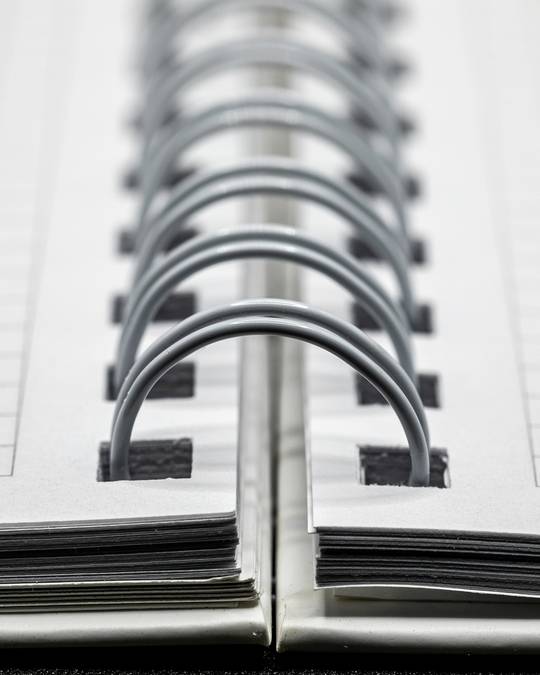 Close-up of the wire spiral binding of an open squared notebook.