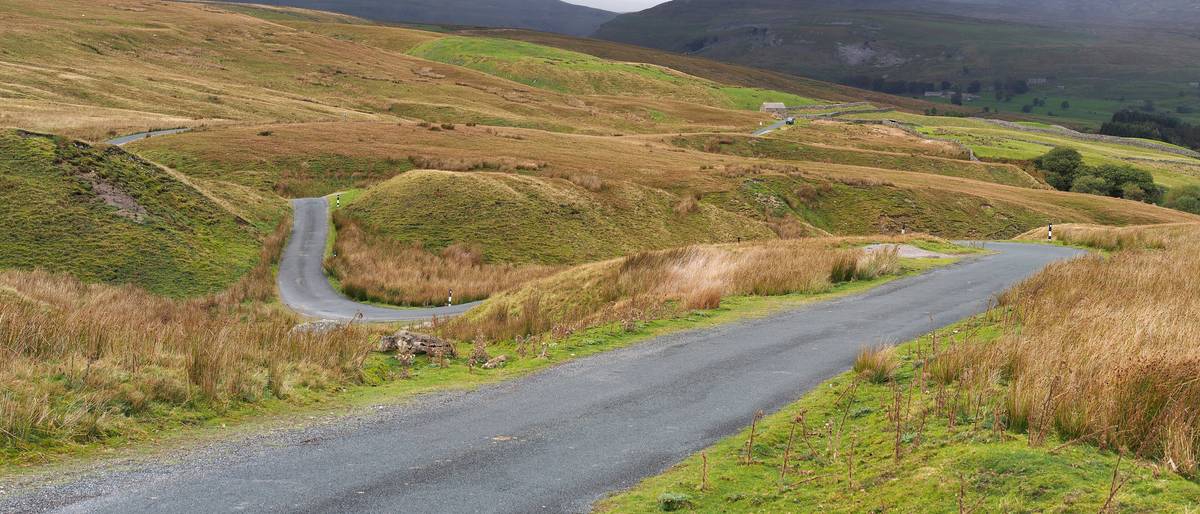 A narrow road winding across open moorland hills.