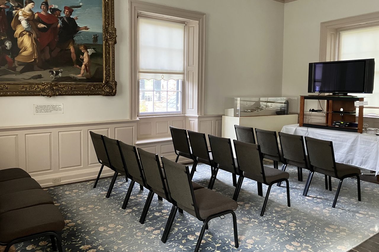 Rows of chairs set out for a talk in a room with a large painting