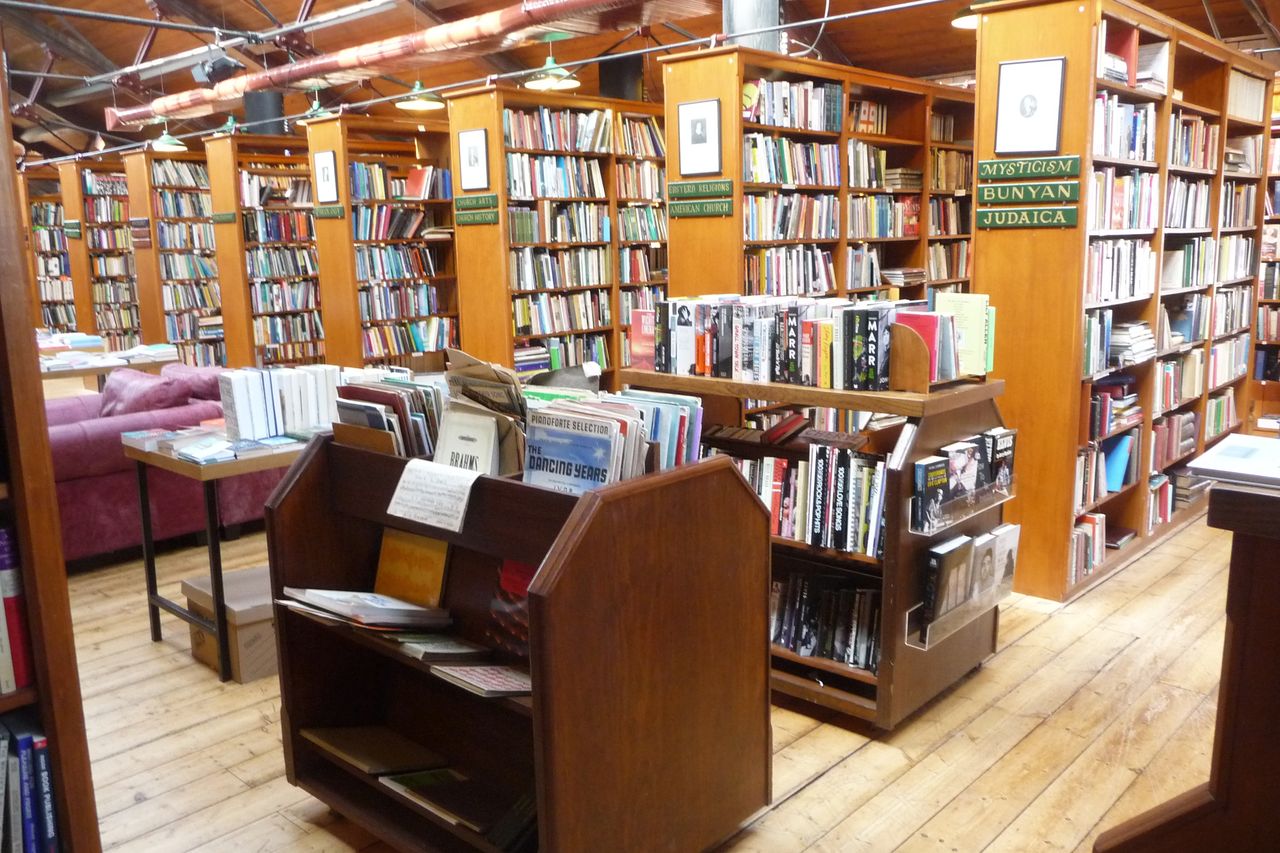 Wooden reading benches between tall bookshelves in a secondhand bookshop