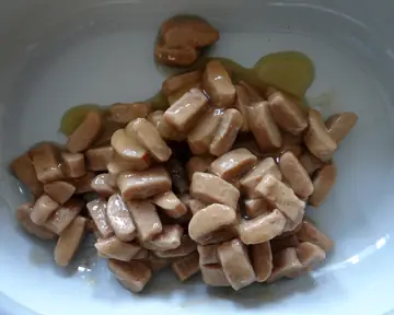 Chunks of wet pet food in a white bowl