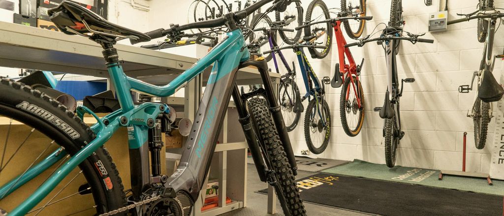 A bike in a repair stand in a workshop with tools on the wall