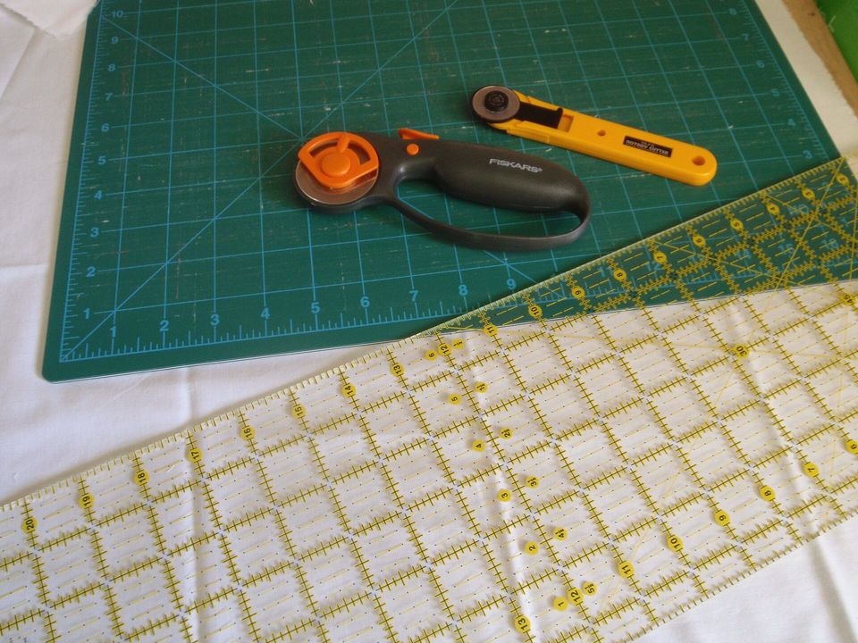 A rotary cutter and a ruler on a green self-healing cutting mat