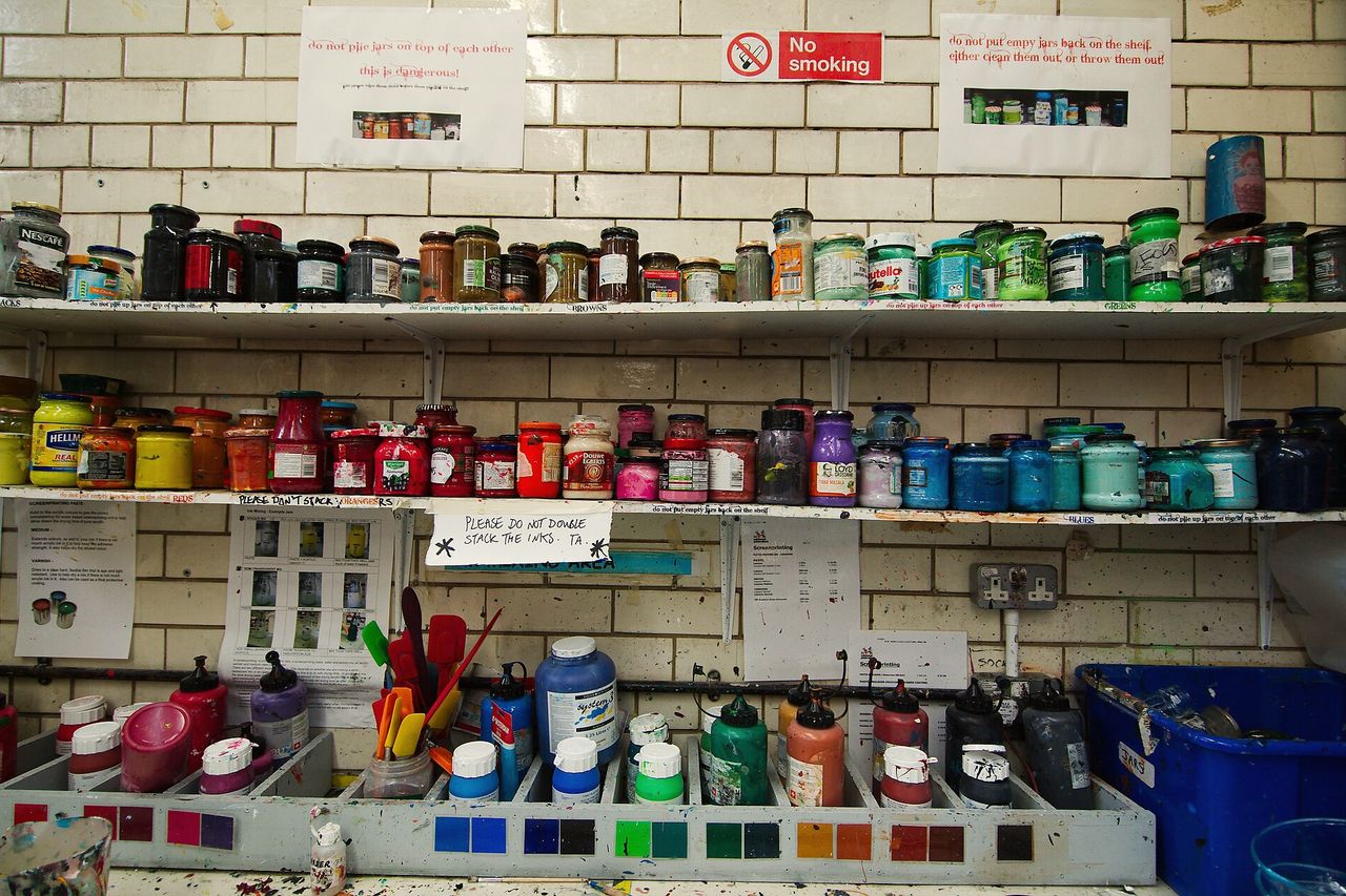 Shelves of ink tins in every colour along a white tiled print-room wall