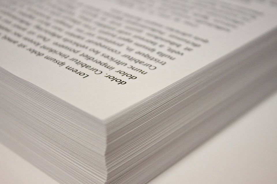 A stack of printed sheets, the top page curling at the corner