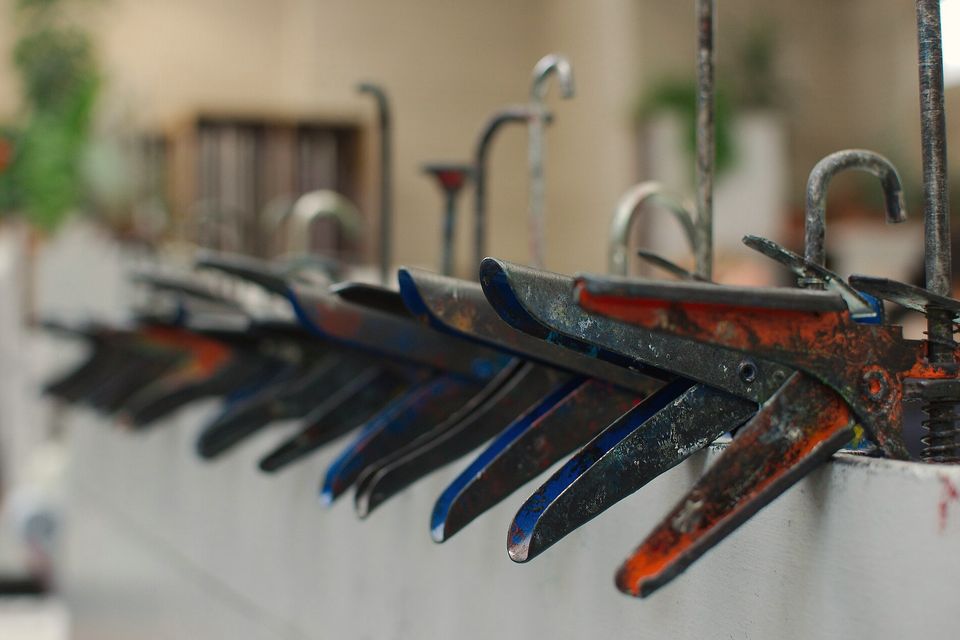 A rack of screen-printing squeegees, blades still stained with ink